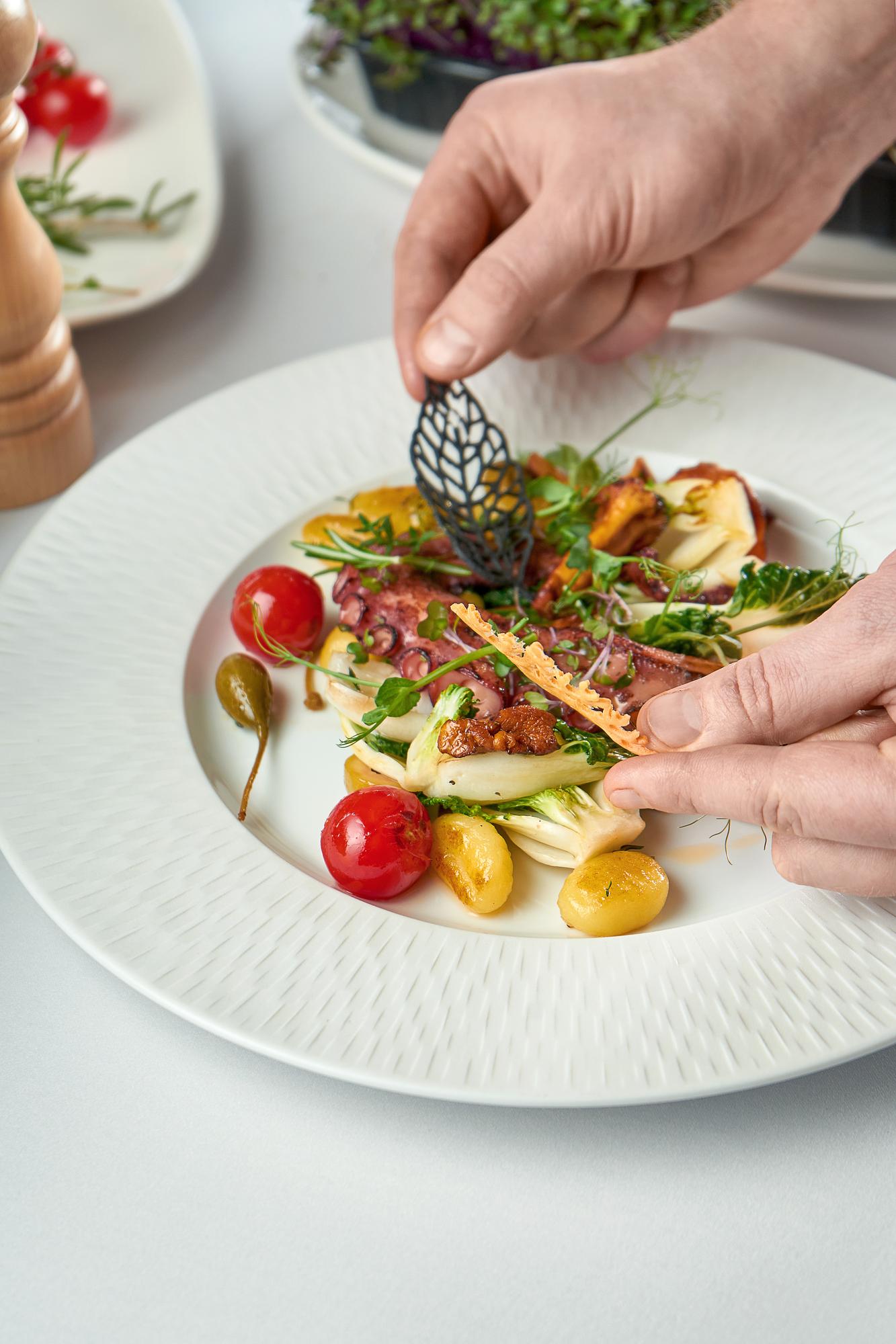 Instructor plating a colorful dish on wooden table